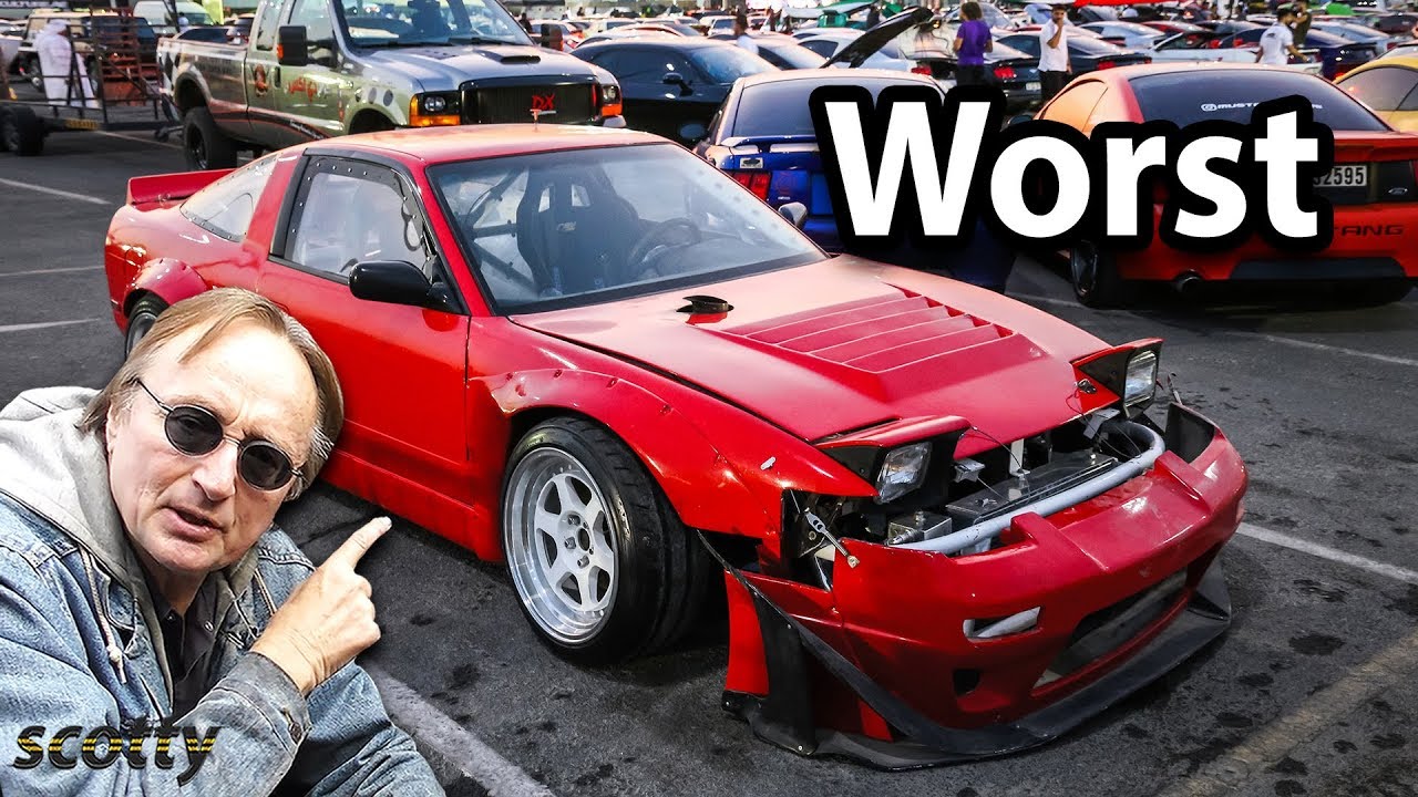 A young car enthusiast standing next to an older project car in a driveway garage with tools laid out