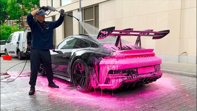Close-up of hands polishing a car's paint with a microfiber cloth, reflections visible in the finish