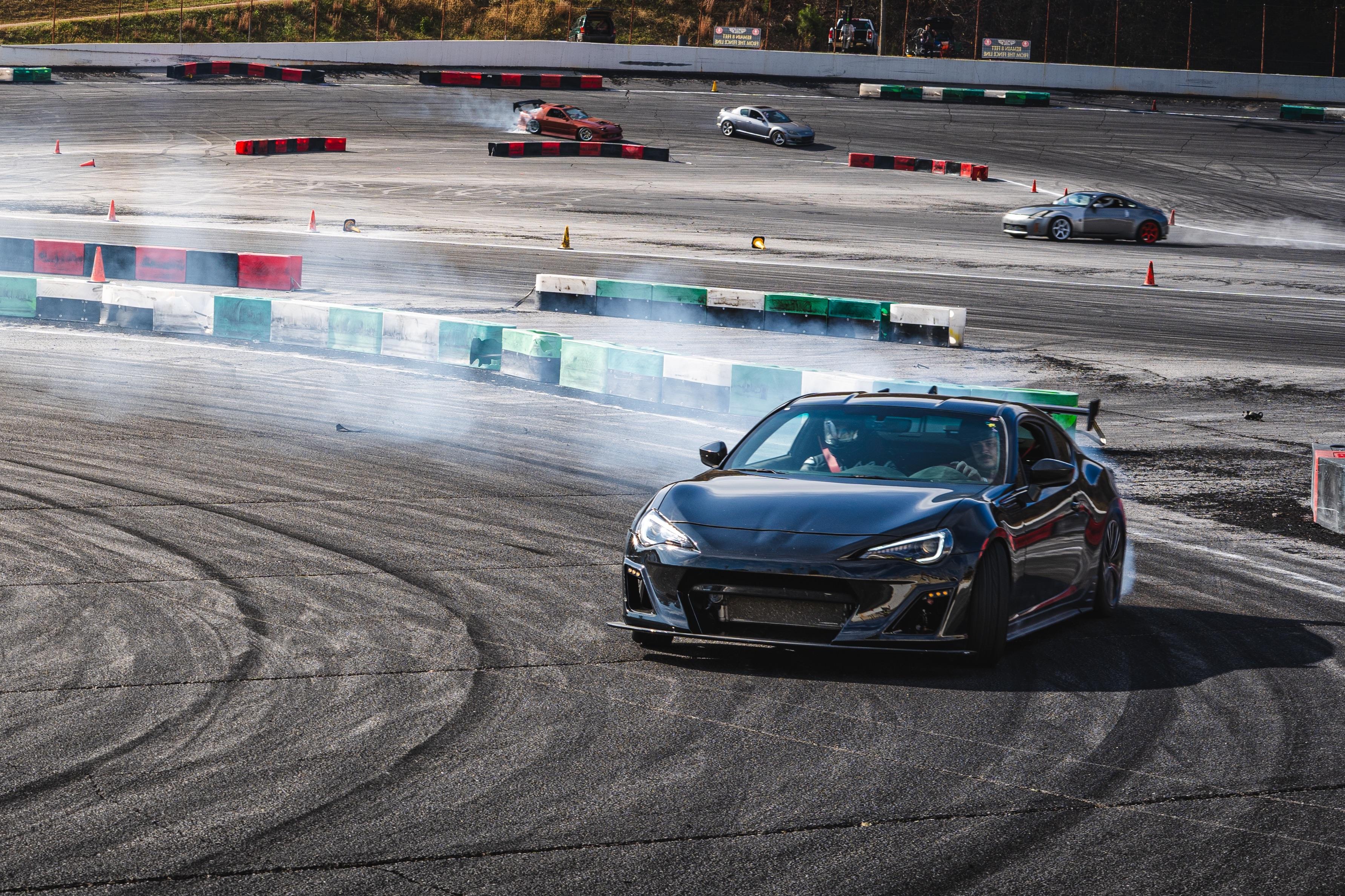 Car sliding sideways in a controlled drift with tire smoke pouring off the rear wheels