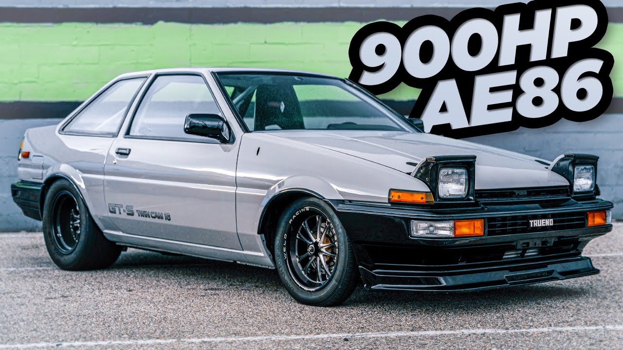 A white and black two-tone Toyota Sprinter Trueno AE86 parked on a mountain road at dusk