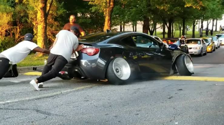 Stanced car with aggressive negative camber and fitment parked at a car meet