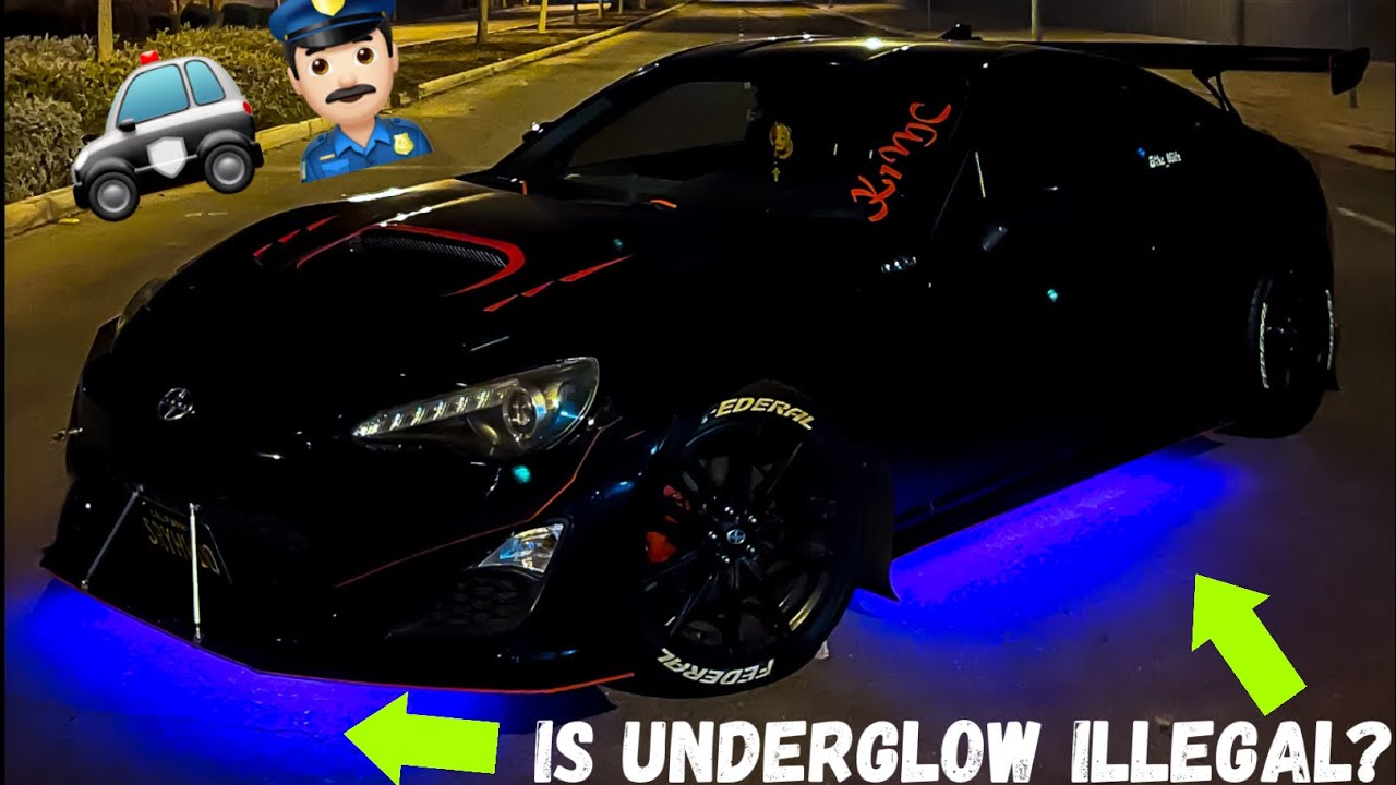 Car parked at night with colorful underglow neon lighting reflecting off wet pavement